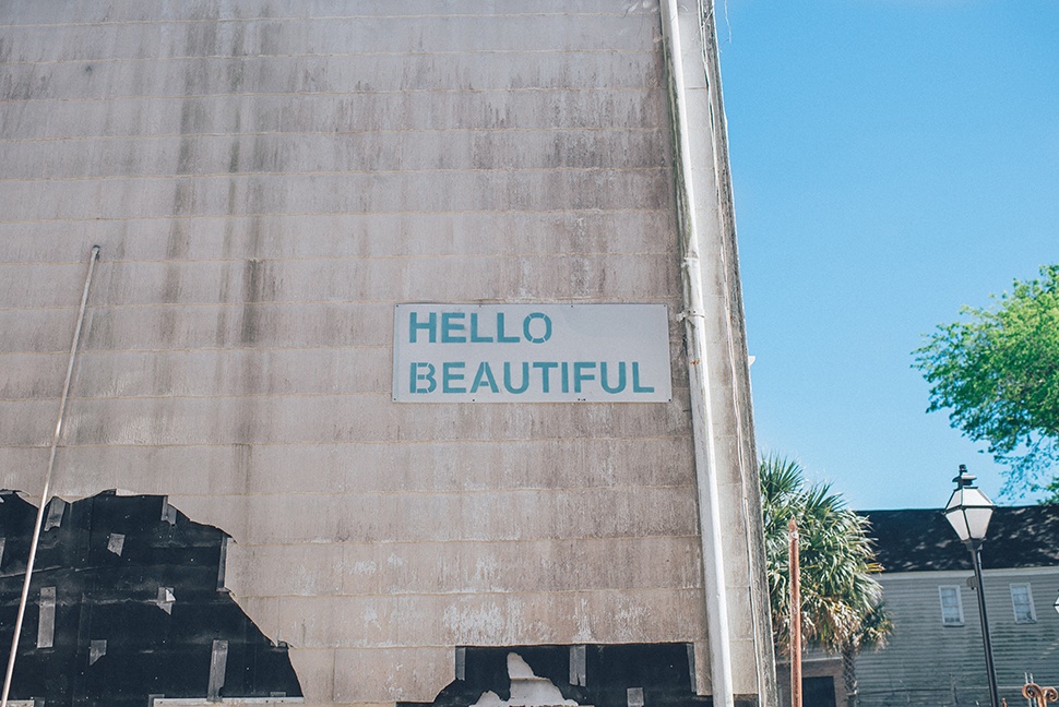Large gray wall outside with the text "HELLO BEAUTIFUL" spelled out on it.