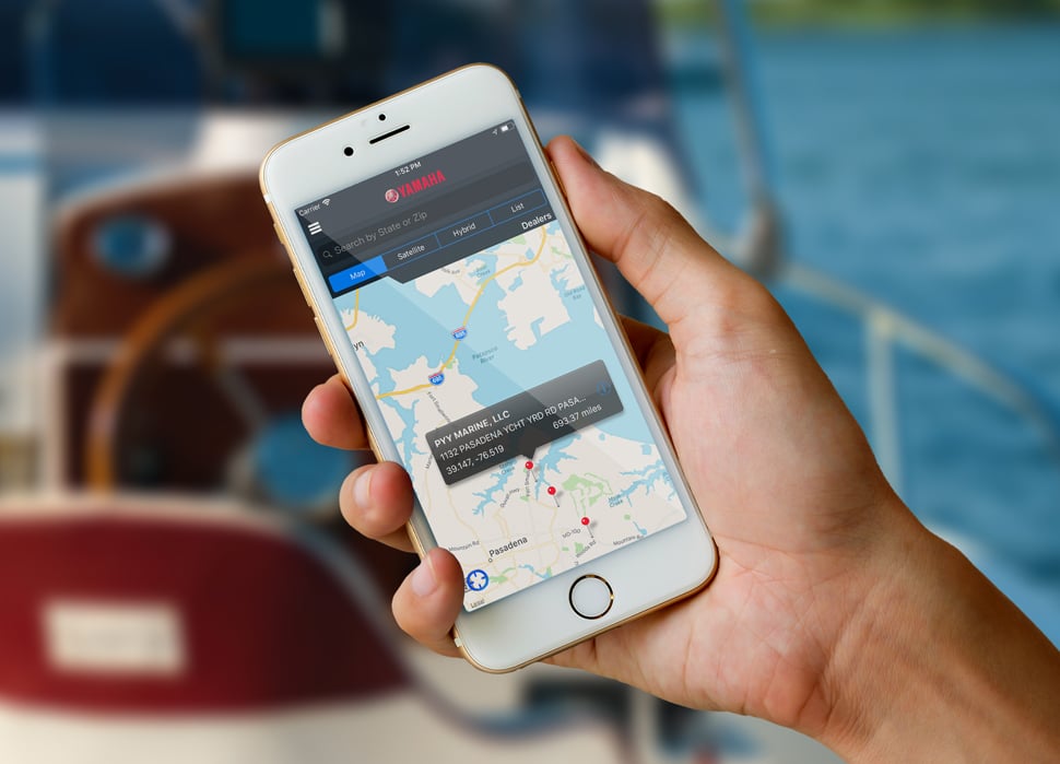 A hand holding a mobile device that displays Yamaha's service locator map