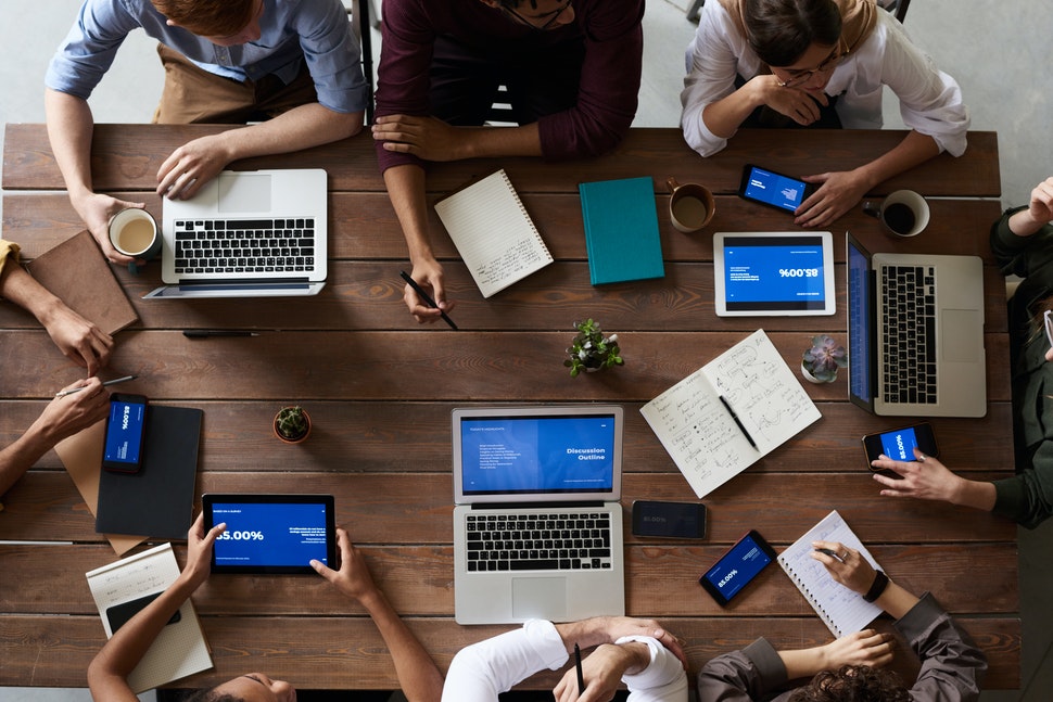 People sitting at a table using laptops and notebooks