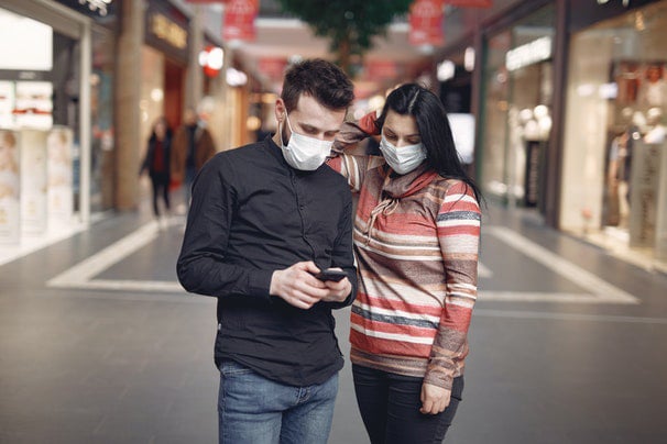 Two shoppers wearing face masks looking at a mobile device